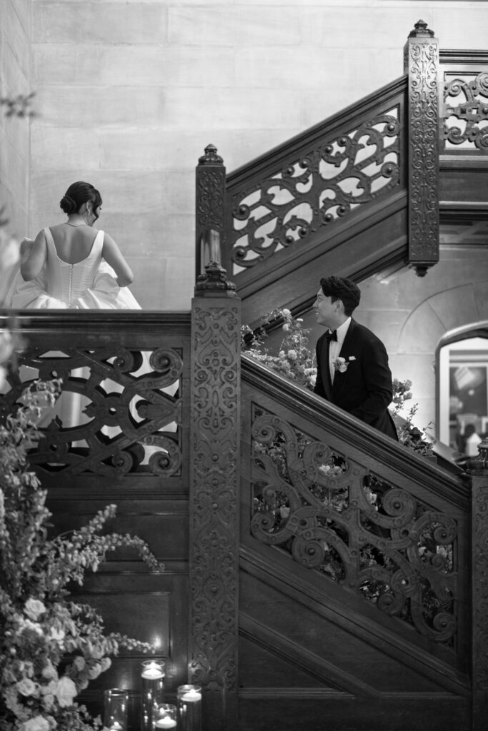 Bride and groom walking down the ornate staircase at Hempstead House wedding venue in Long Island.