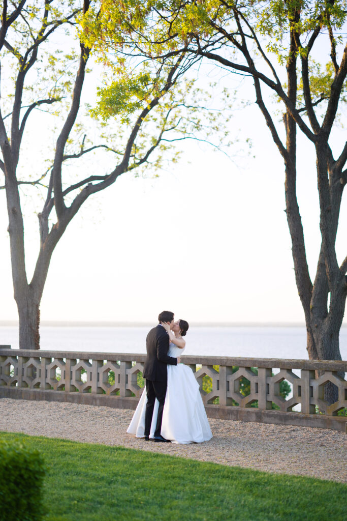 Bride and groom walking hand in hand on terrace at Hempstead House mansion.
