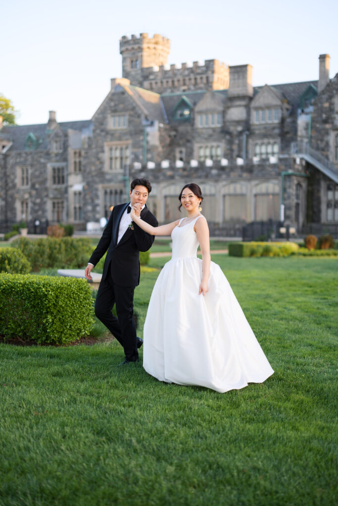 Bride and groom walking hand in hand on terrace at Hempstead House mansion.
