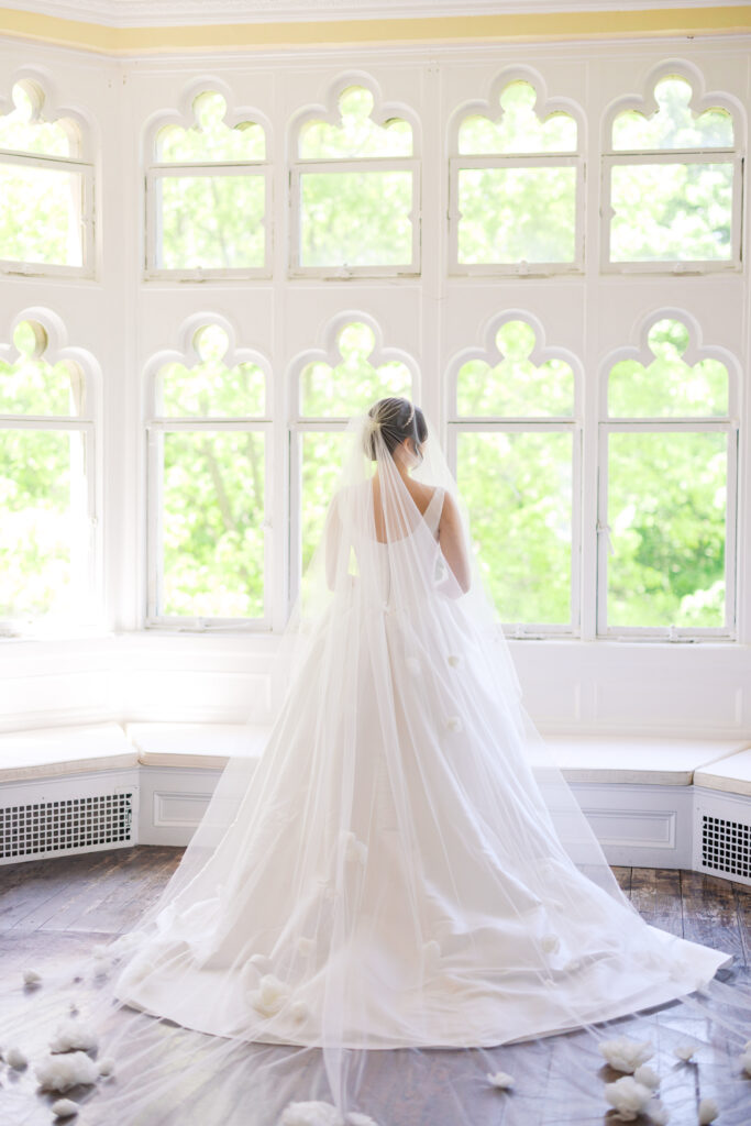 Bride in full wedding gown posing in Hempstead House solarium.