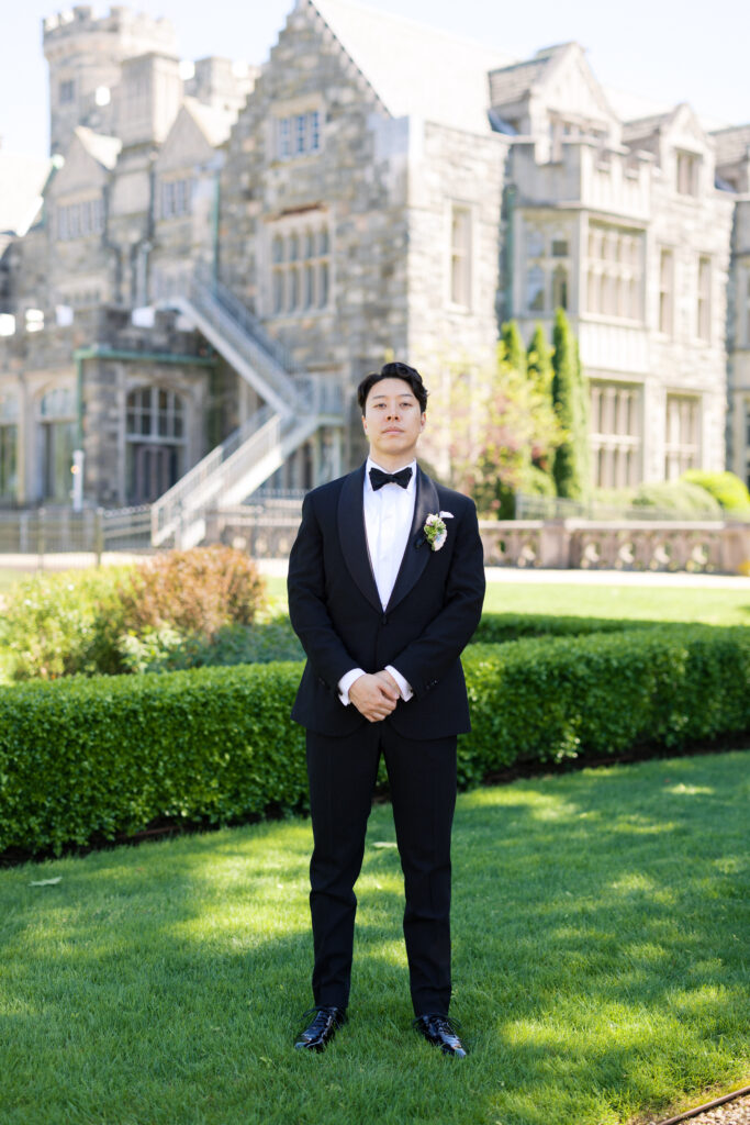 Groom standing outside Hempstead House stone facade in Long Island.