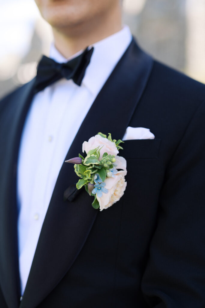Groom standing outside Hempstead House stone facade in Long Island.