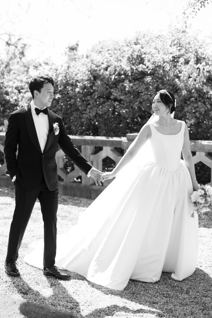 Bride and groom walking hand in hand on terrace at Hempstead House mansion.