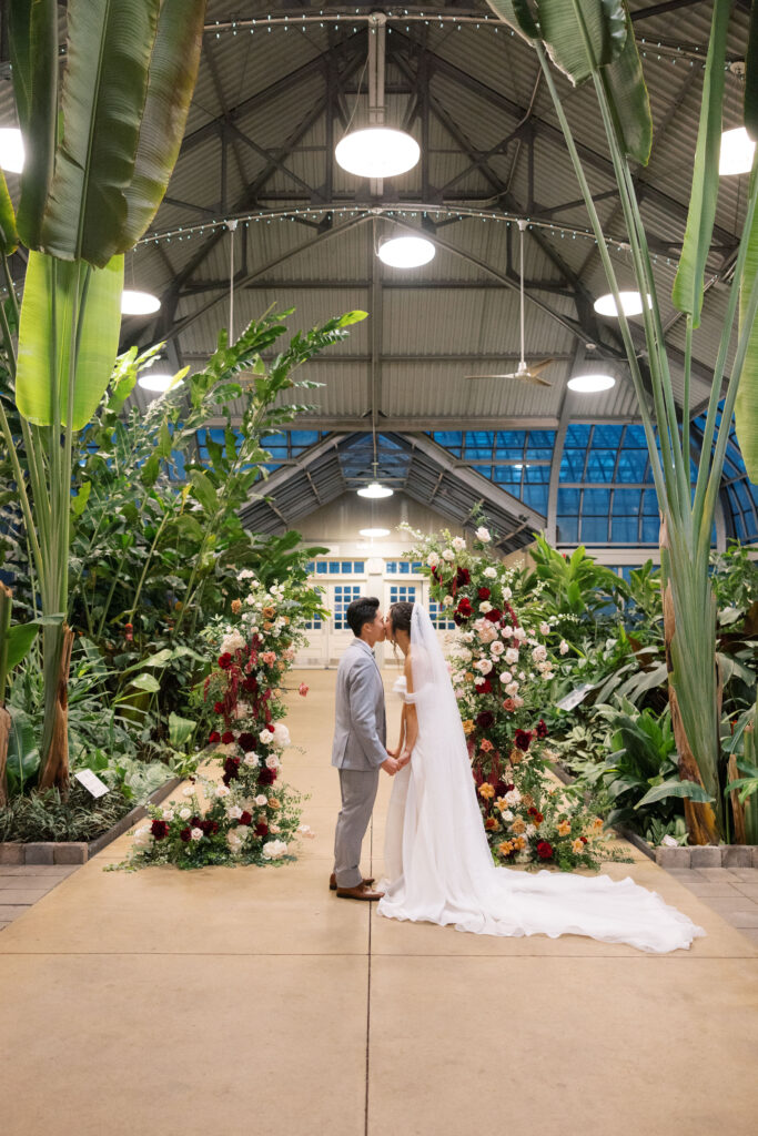 A stunning fall wedding at Garfield Park Conservatory in Chicago. The vibrant autumn foliage serves as a breathtaking backdrop for a couple’s ceremony in the Horticulture Hall, with floor-to-ceiling windows letting in the perfect natural light. Captured by Violet Carter Photography.