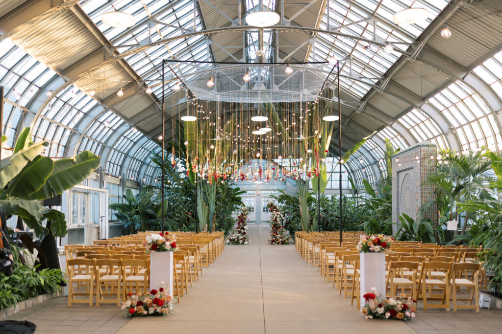 A stunning fall wedding at Garfield Park Conservatory in Chicago. The vibrant autumn foliage serves as a breathtaking backdrop for a couple’s ceremony in the Horticulture Hall, with floor-to-ceiling windows letting in the perfect natural light. Captured by Violet Carter Photography.