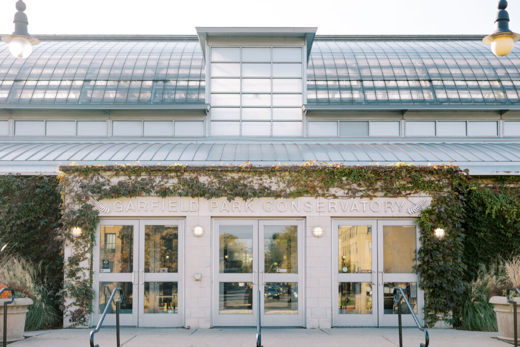 A stunning fall wedding at Garfield Park Conservatory in Chicago. The vibrant autumn foliage serves as a breathtaking backdrop for a couple’s ceremony in the Horticulture Hall, with floor-to-ceiling windows letting in the perfect natural light. Captured by Violet Carter Photography.